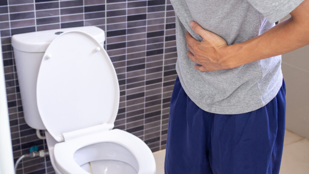 Homem no banheiro, pensando em como o HoLEP evita complicações urinárias